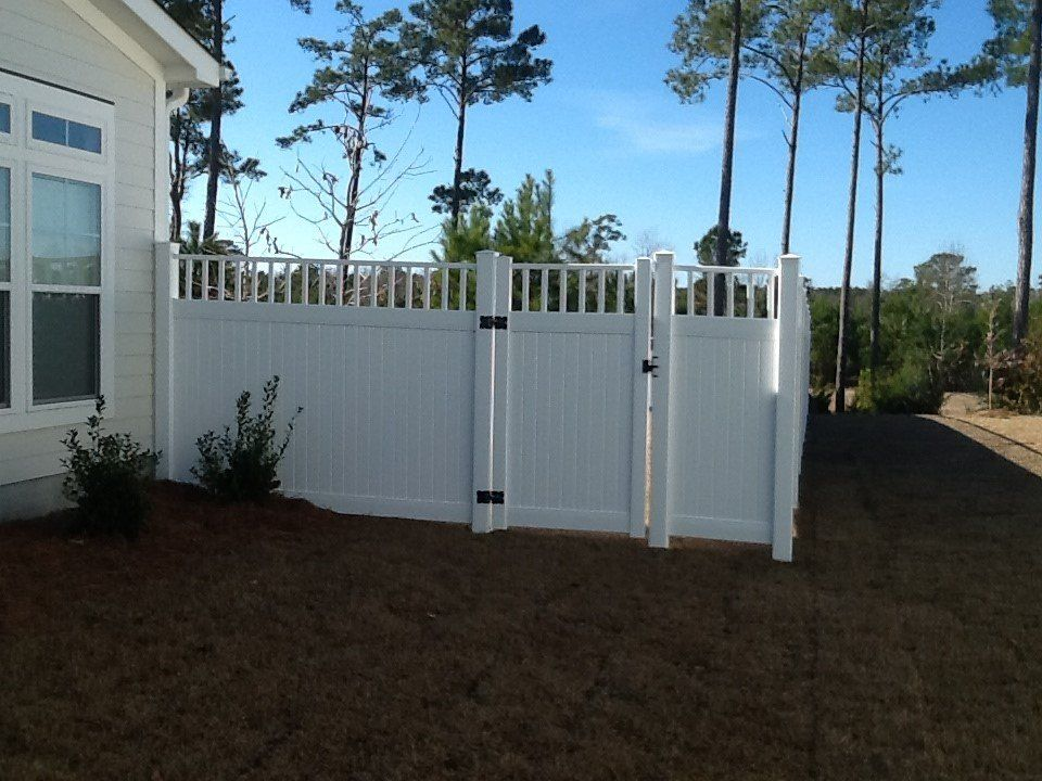 A white fence with a gate in front of a house