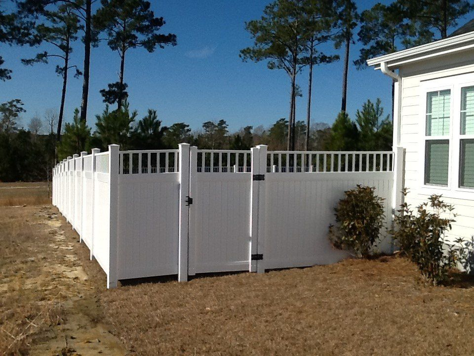 A white fence with a gate in front of a house