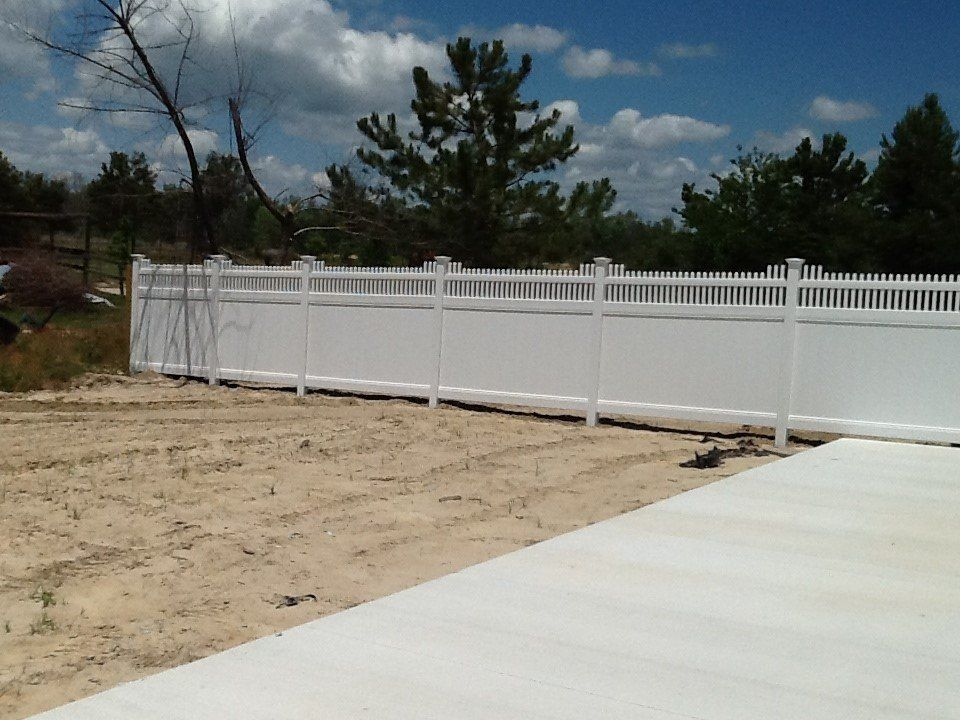 A white fence is in the middle of a dirt field