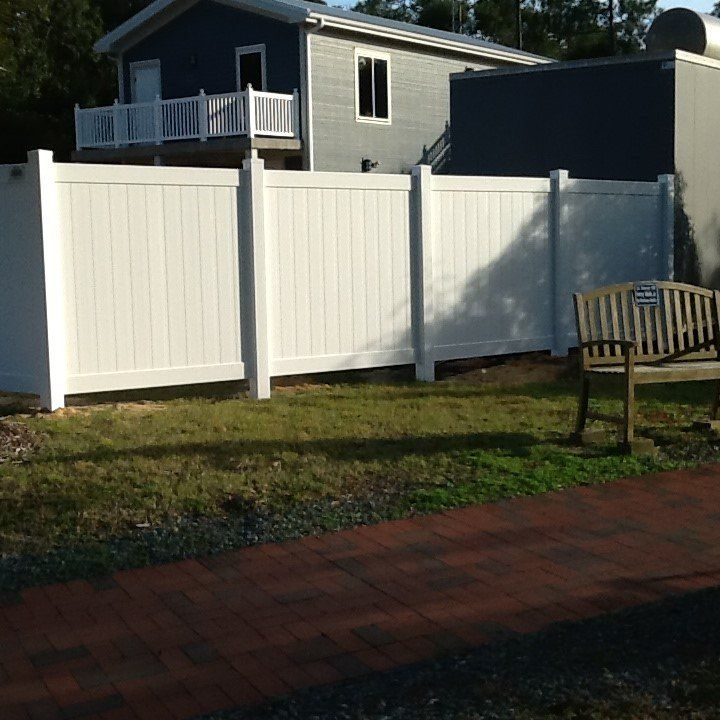 A white fence with a wooden bench in front of it