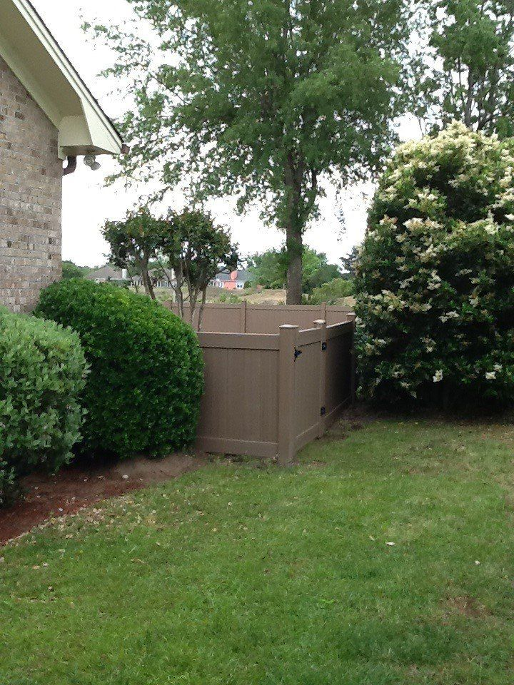 A brown fence surrounds a lush green yard