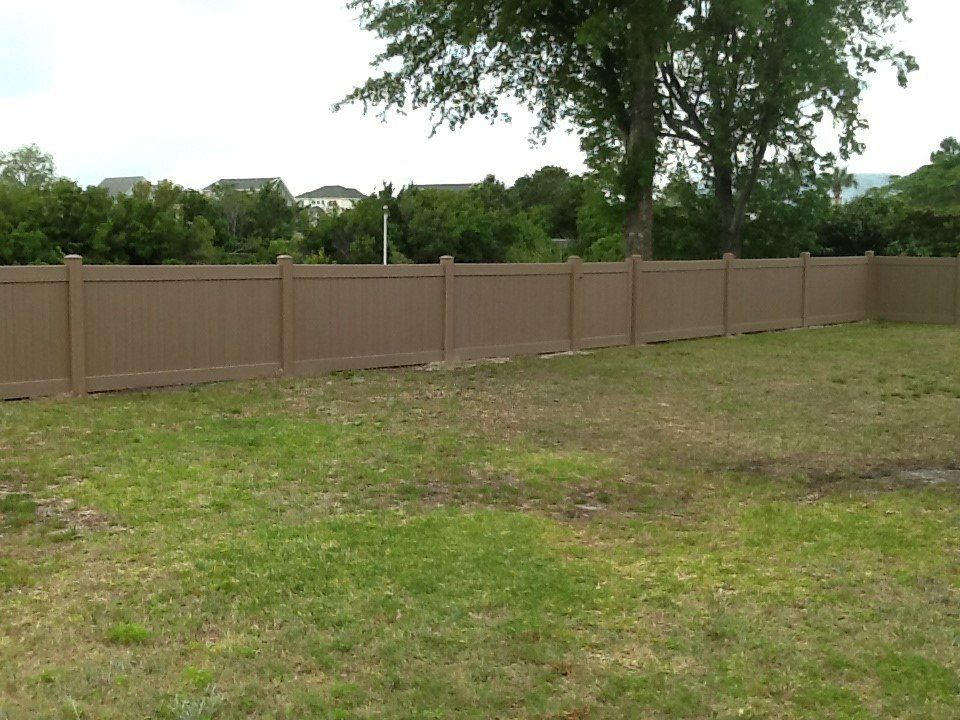 A brown fence surrounds a lush green field