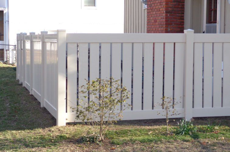 A white fence is sitting in the grass in front of a house.