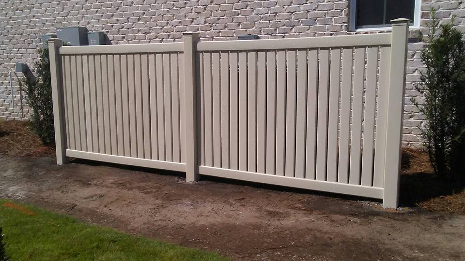 A white fence is surrounded by gravel and plants