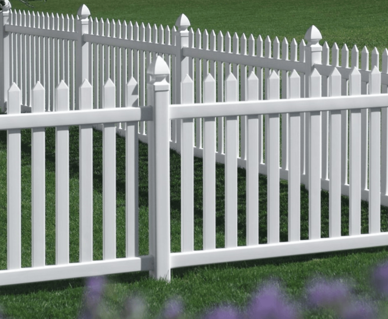 A white picket fence surrounds a lush green field