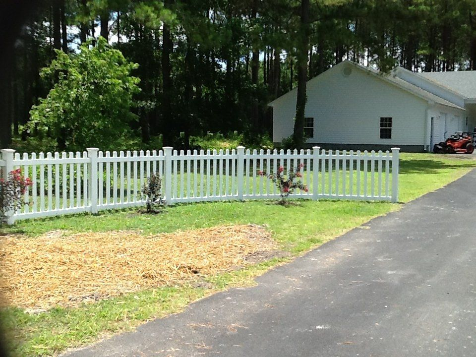 A white picket fence is in front of a white house