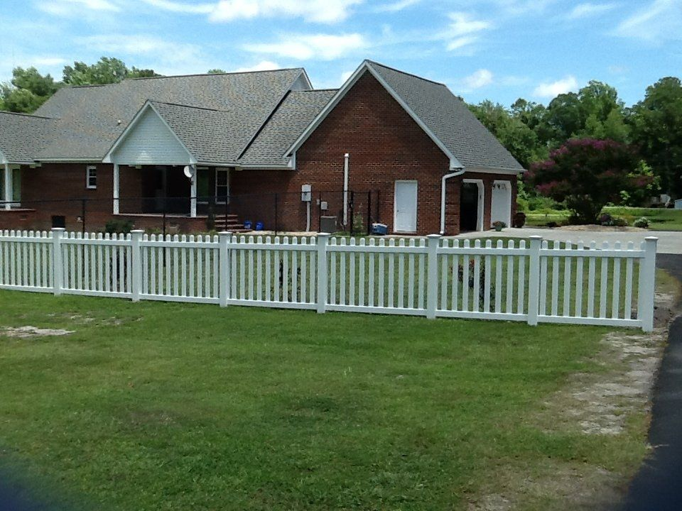 A brick house with a white picket fence in front of it