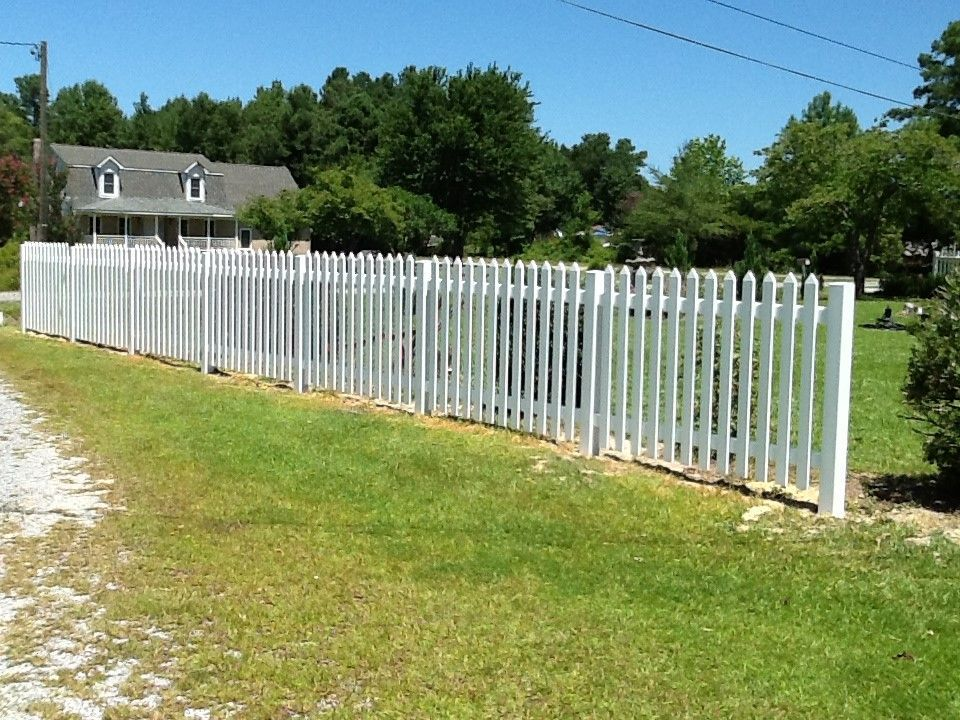 A white picket fence with a house in the background
