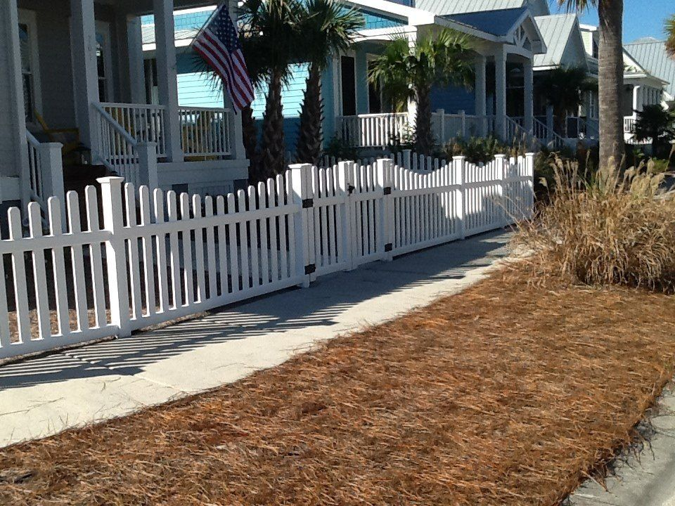 A white picket fence surrounds a house with a porch