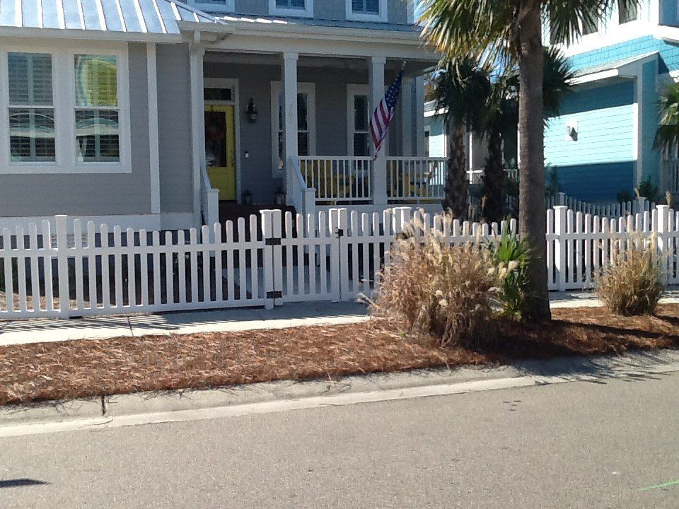 A white picket fence surrounds a house with a porch