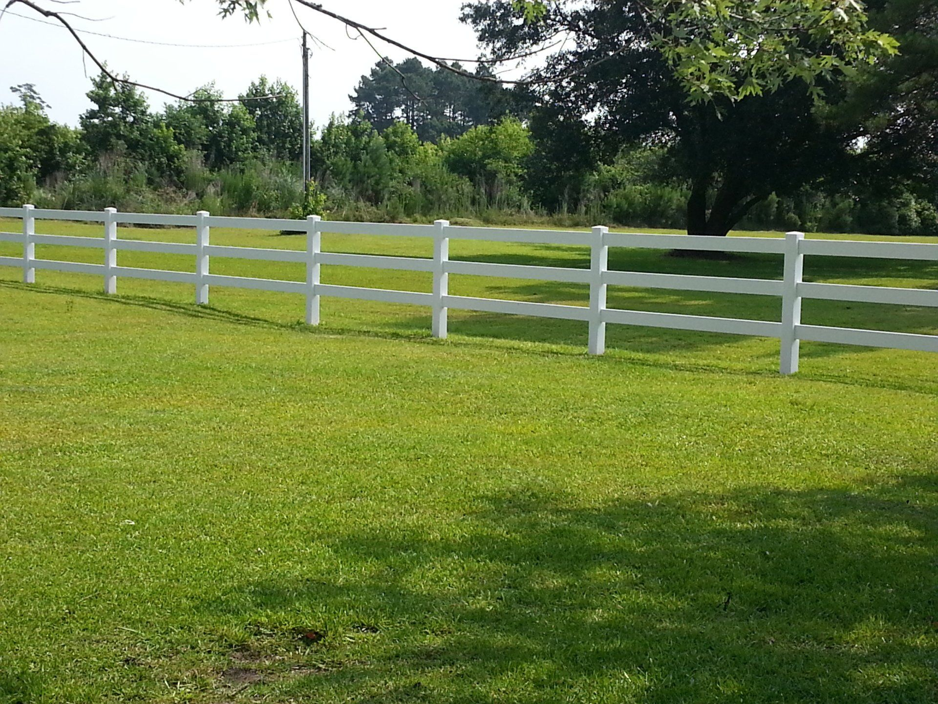 A white fence surrounds a lush green field