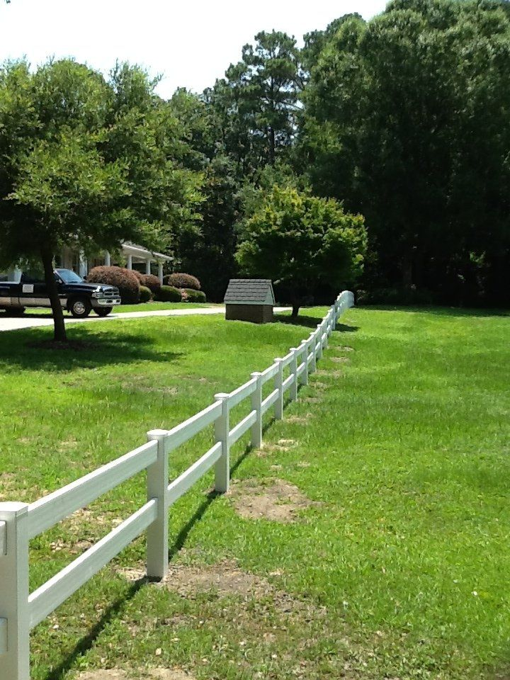 A white fence surrounds a lush green field