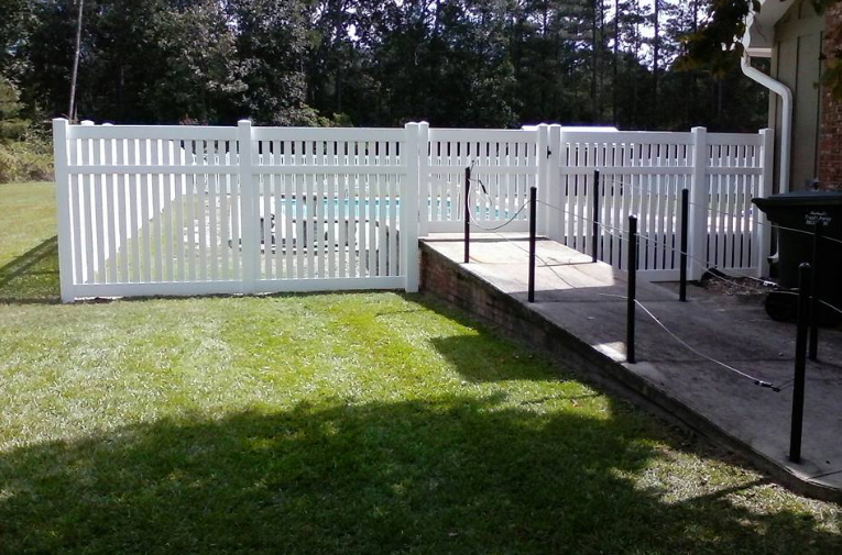 A white fence surrounds a swimming pool in a backyard