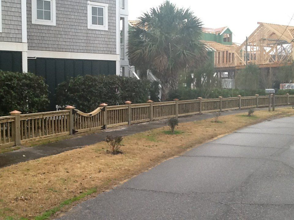 A wooden fence along a sidewalk in front of a house