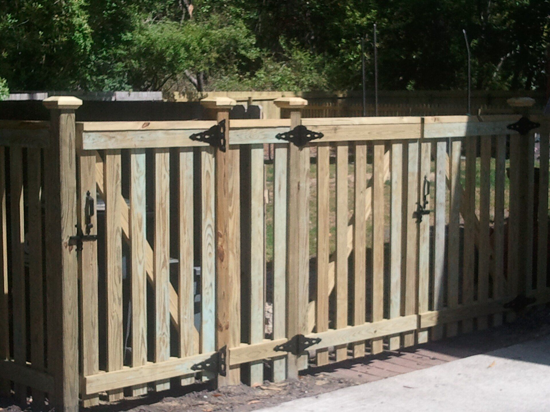 A wooden fence with a gate and trees in the background