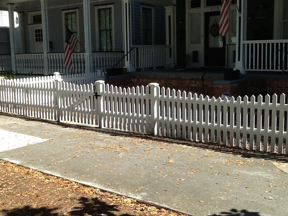 A white picket fence surrounds a house with a porch