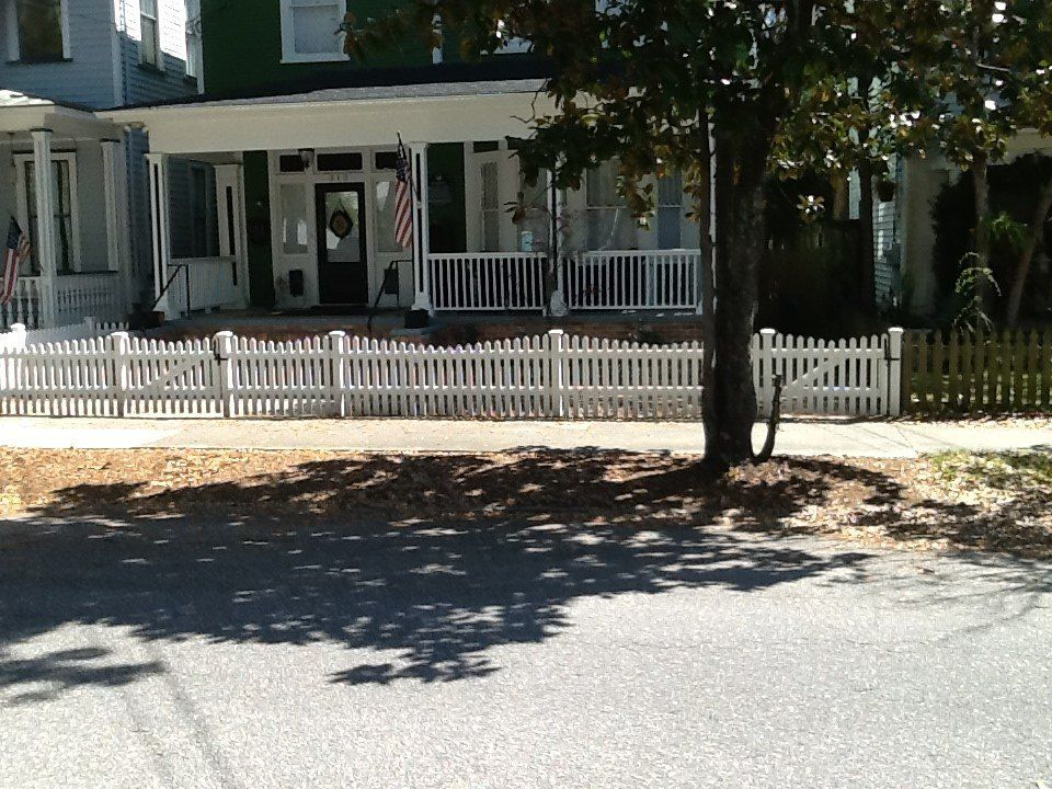 A white picket fence surrounds a house with a porch