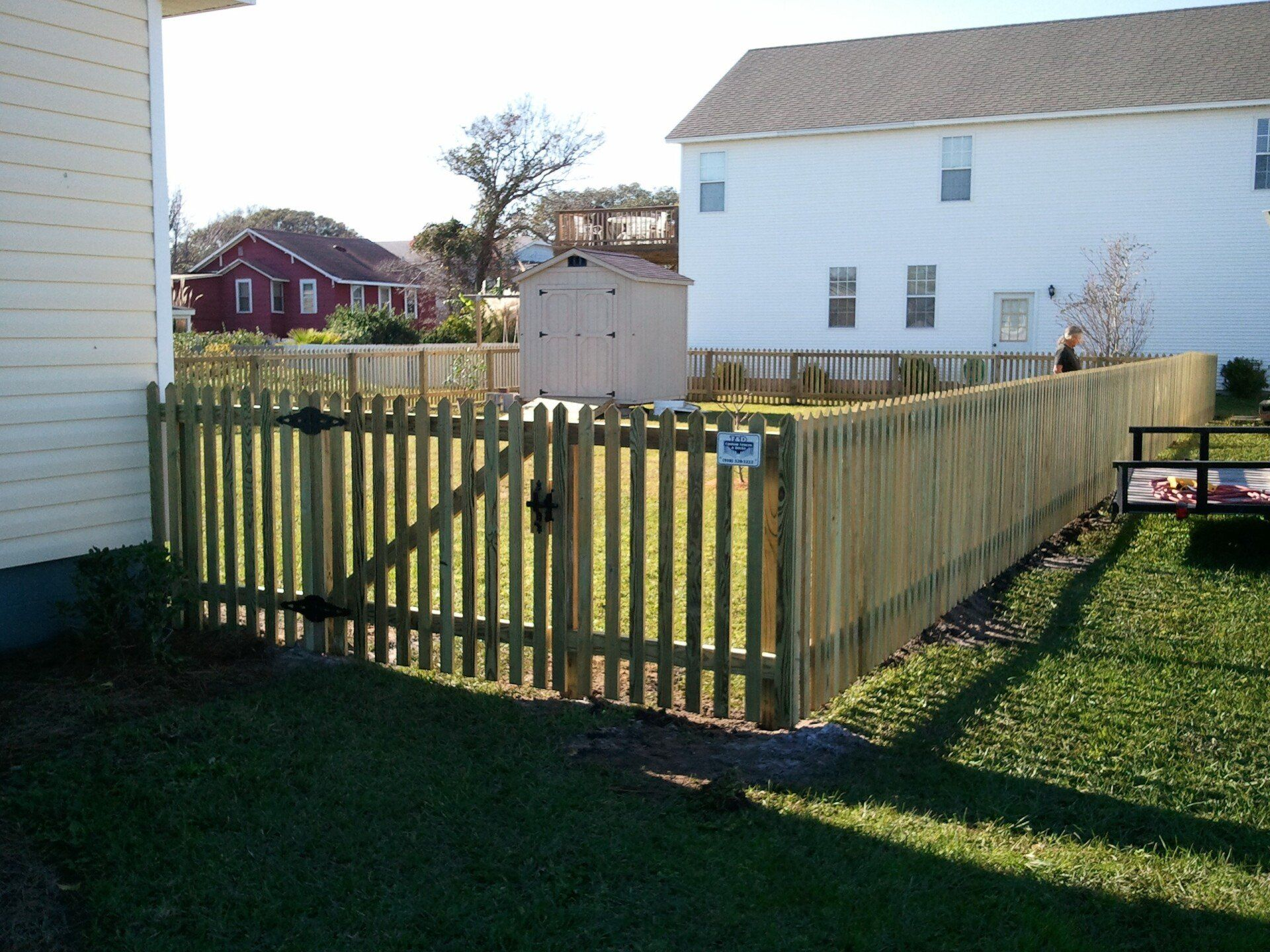 A white picket fence surrounds a house with a porch