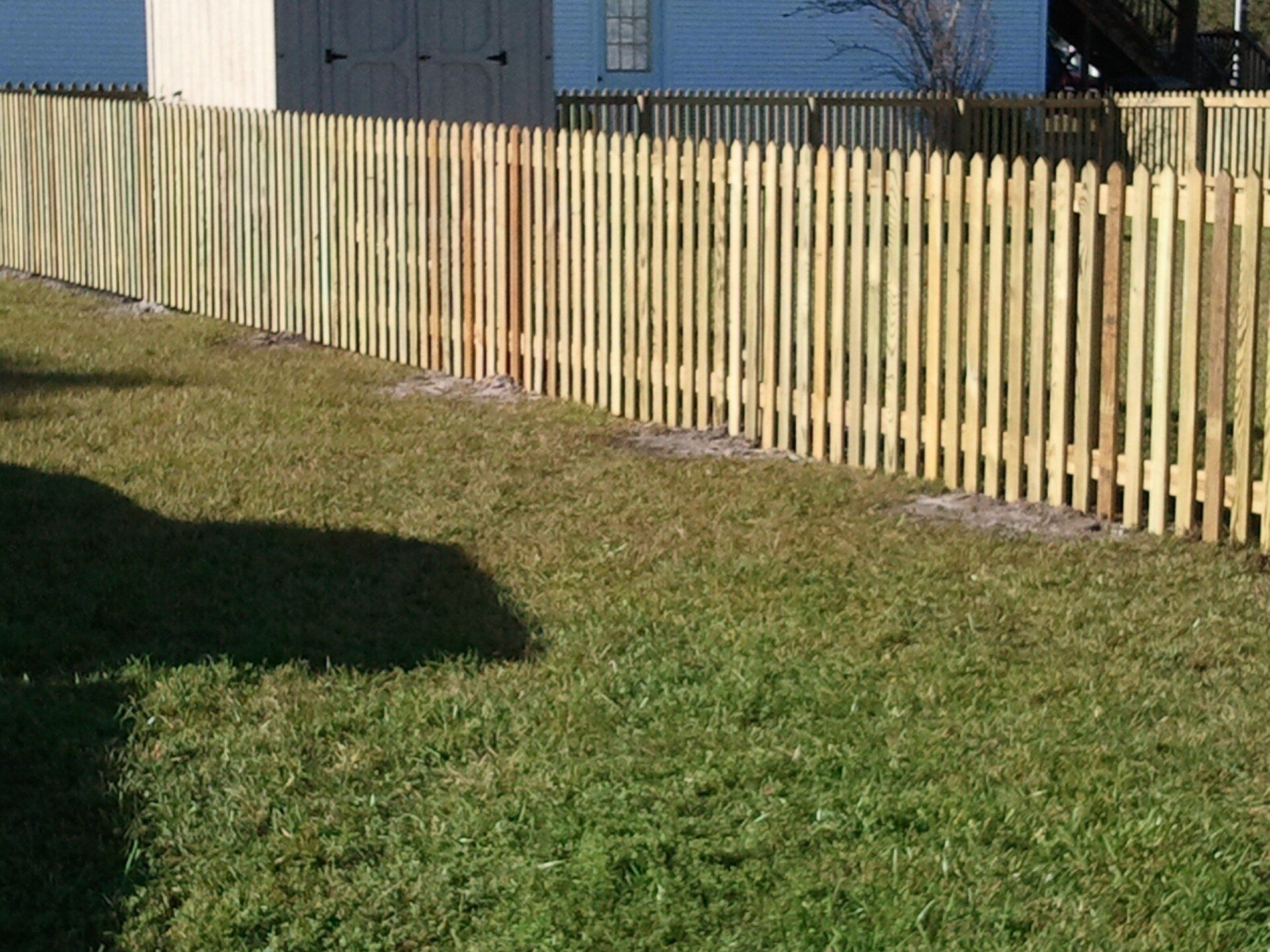 A wooden picket fence surrounds a lush green yard