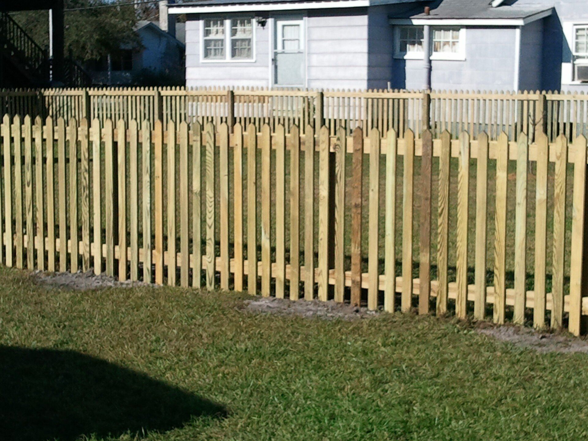 A wooden picket fence in front of a house