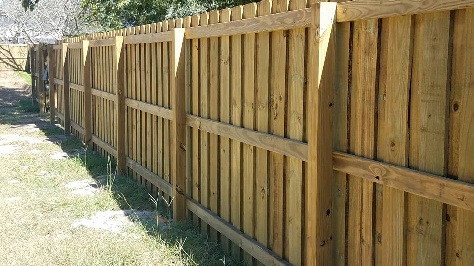 A wooden fence is sitting on top of a lush green field.