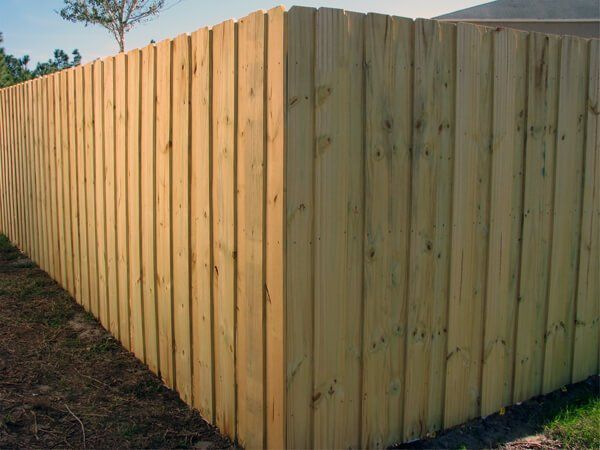 A wooden fence is sitting in the grass next to a house.