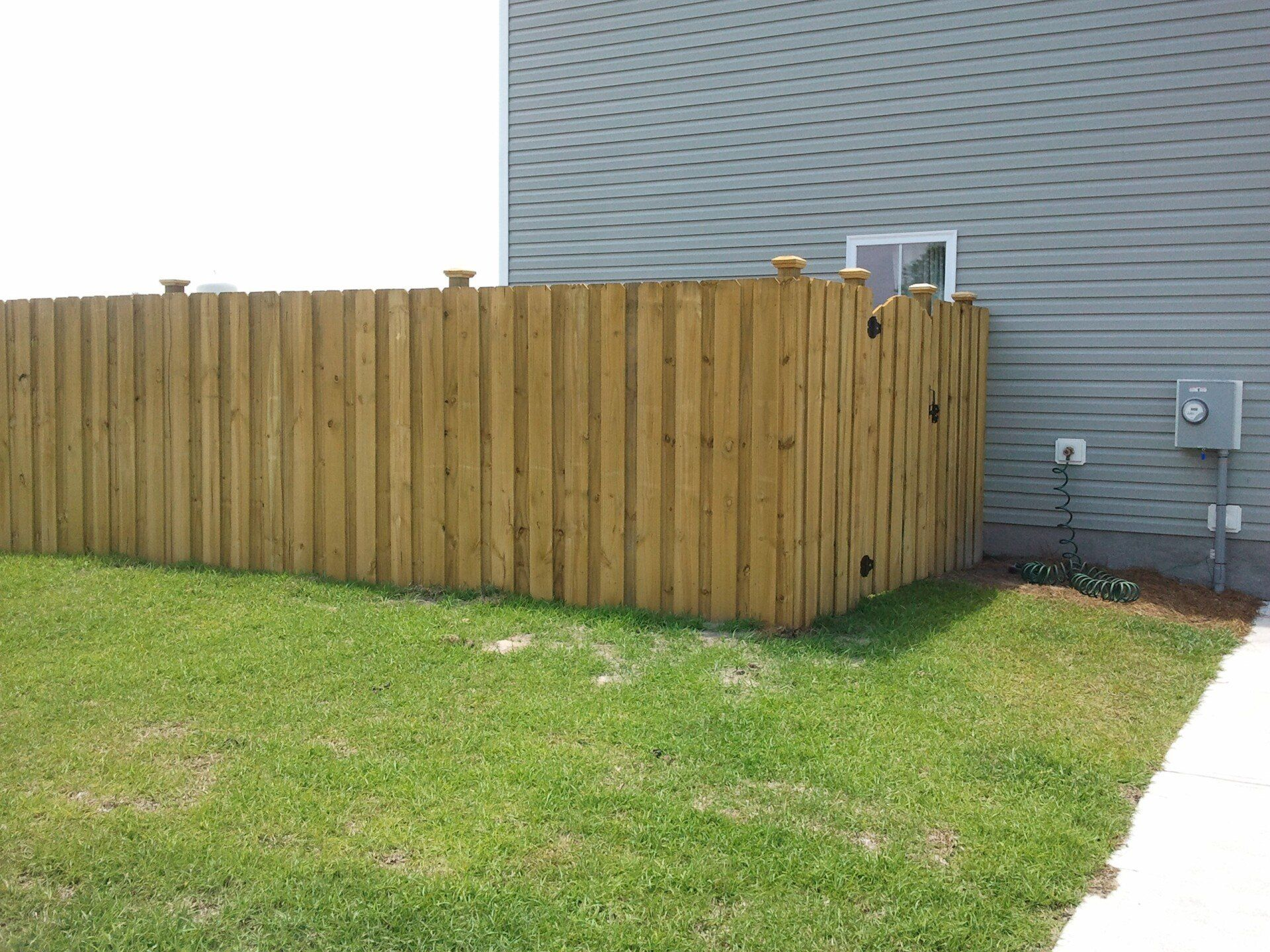 A wooden fence is in the backyard of a house.
