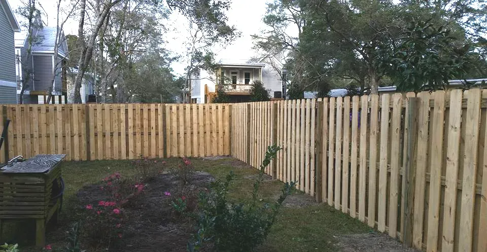 A wooden fence is sitting in the middle of a lush green field.