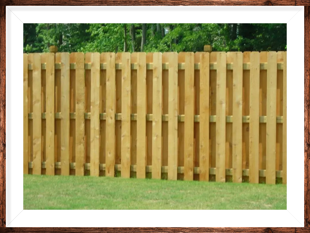 A wooden fence is sitting in the middle of a lush green field.