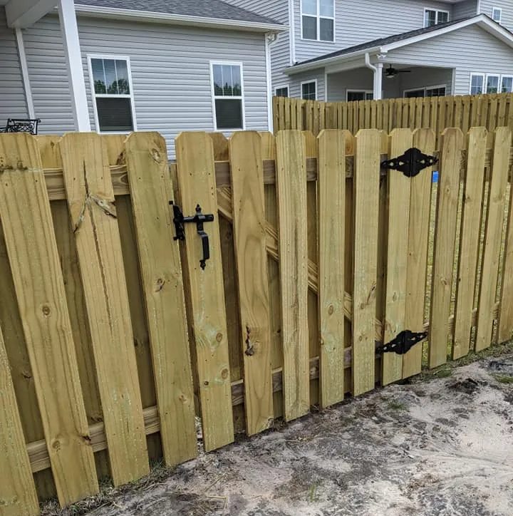 A wooden fence with a gate in front of a house
