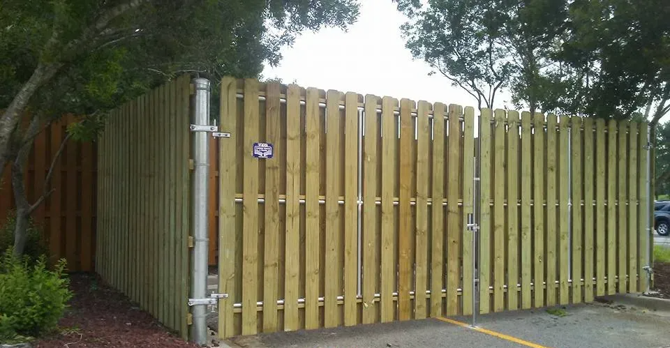 A wooden fence is surrounding a parking lot.