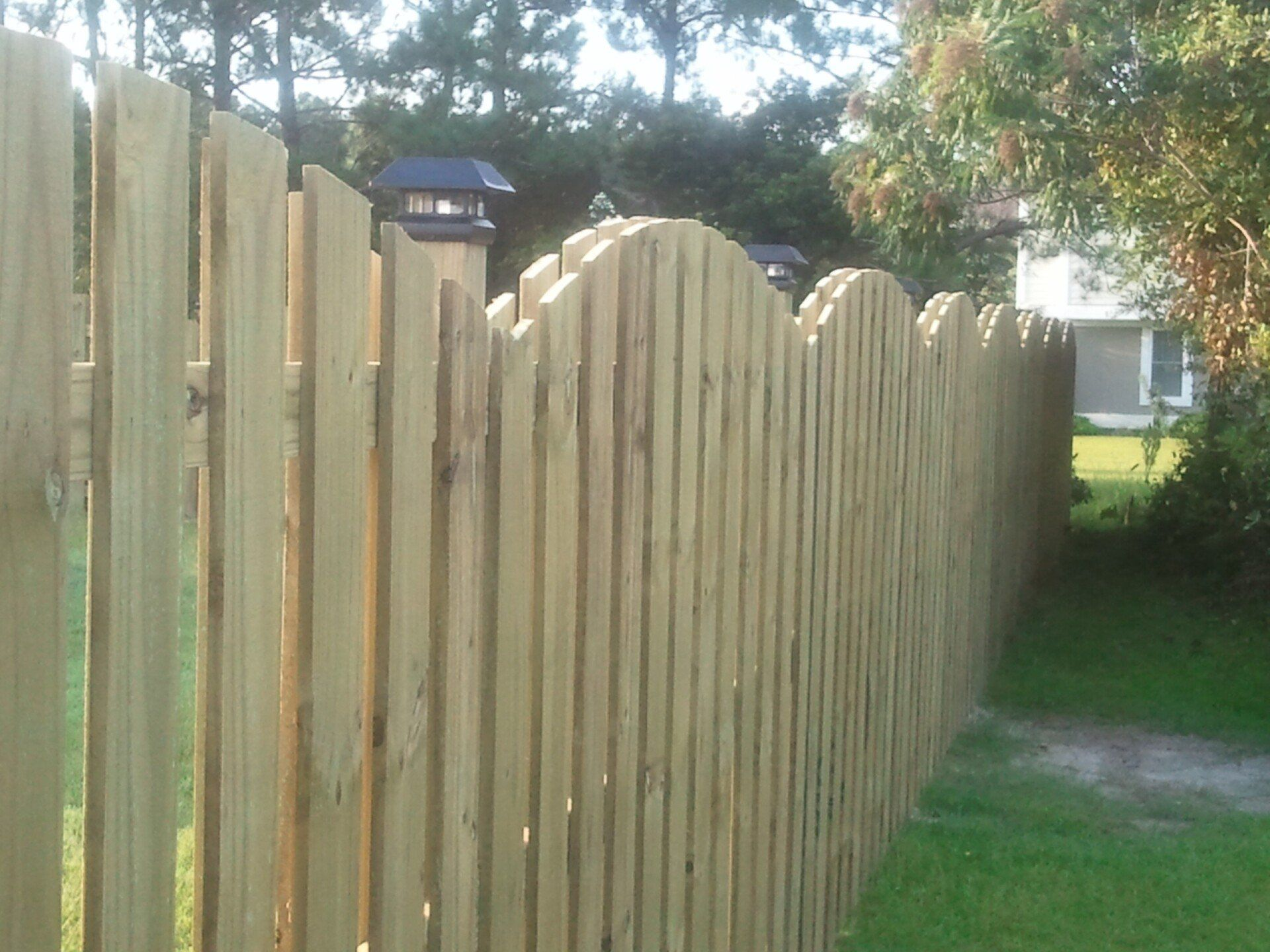 A wooden fence is surrounded by green grass and trees.