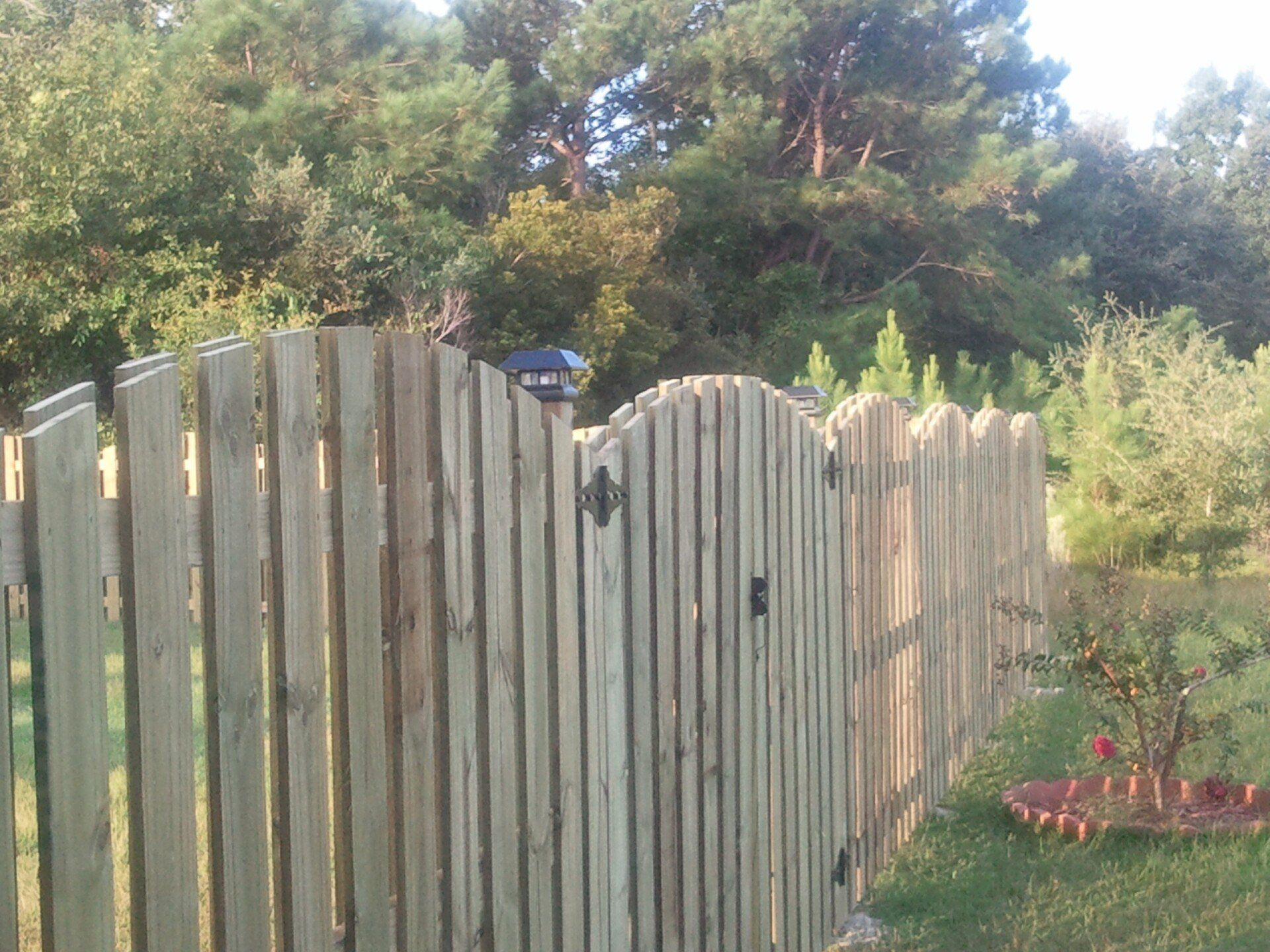 A wooden fence with a gate and trees in the background