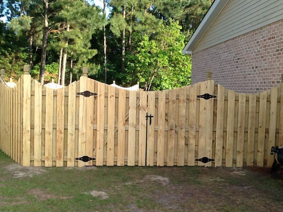 A wooden fence with a gate in front of a brick house