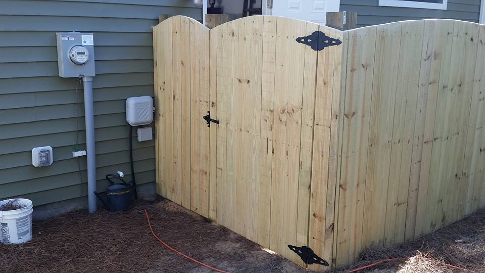A wooden fence with a gate in the backyard of a house.