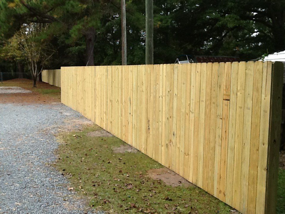A long wooden fence along a gravel road