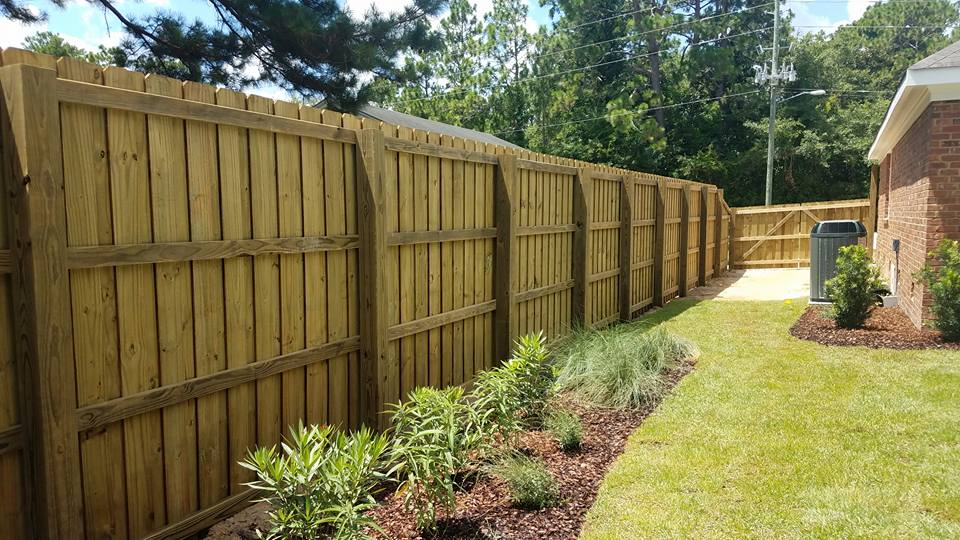 A wooden fence is in the backyard of a house.