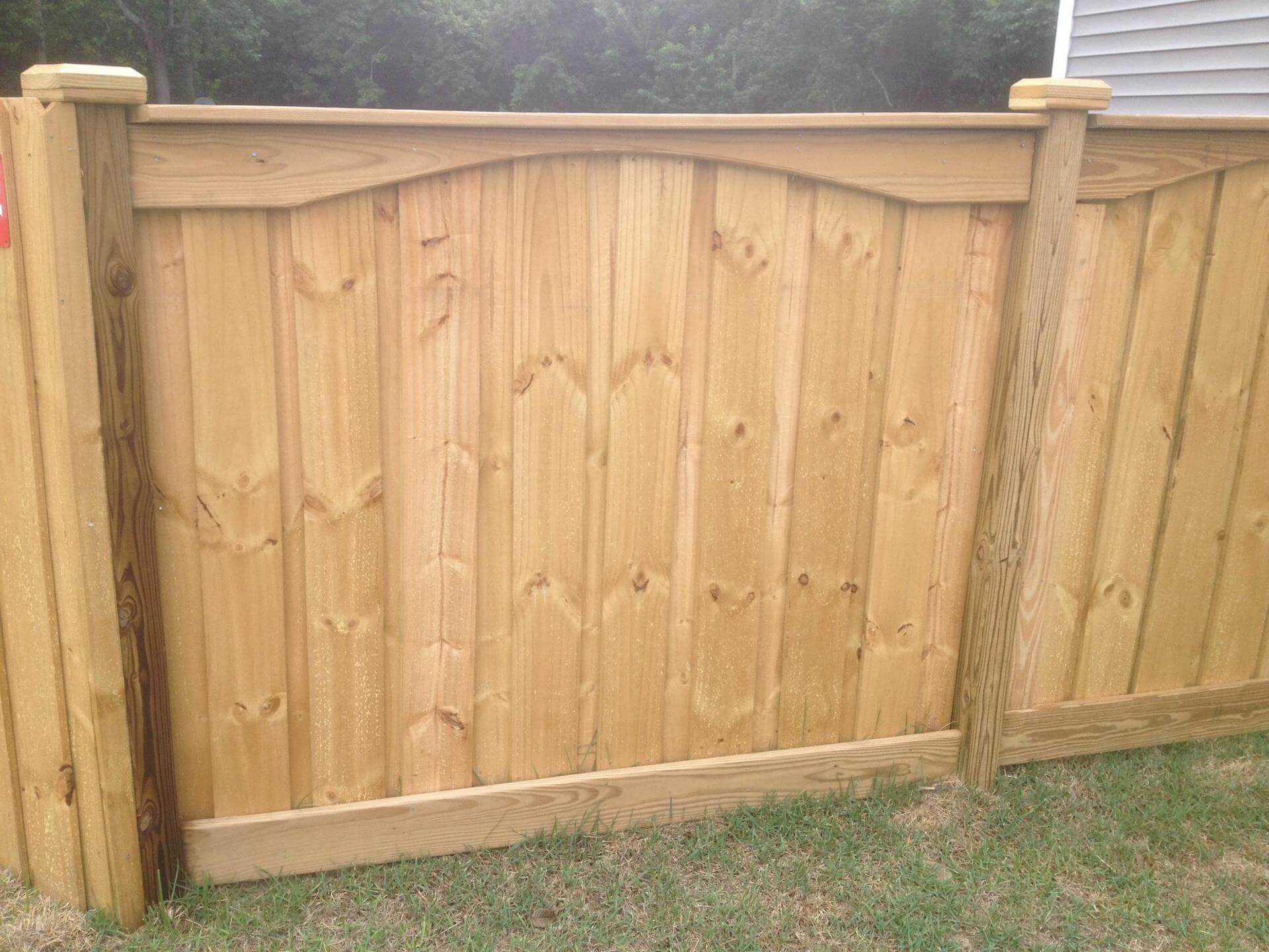 A wooden fence is sitting in the grass in front of a house.