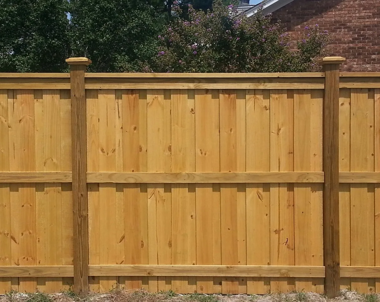 A wooden fence with a brick house in the background