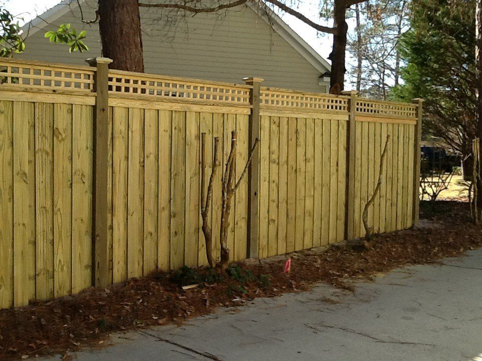 A wooden fence with a lattice top is in front of a house