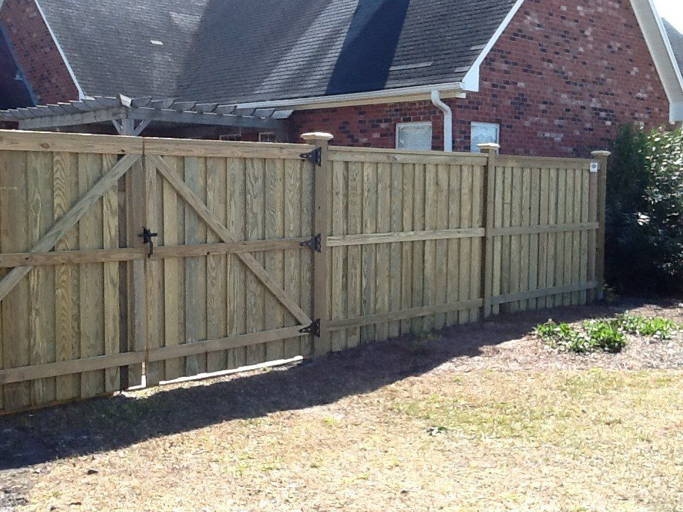 A wooden fence with a gate in front of a brick house