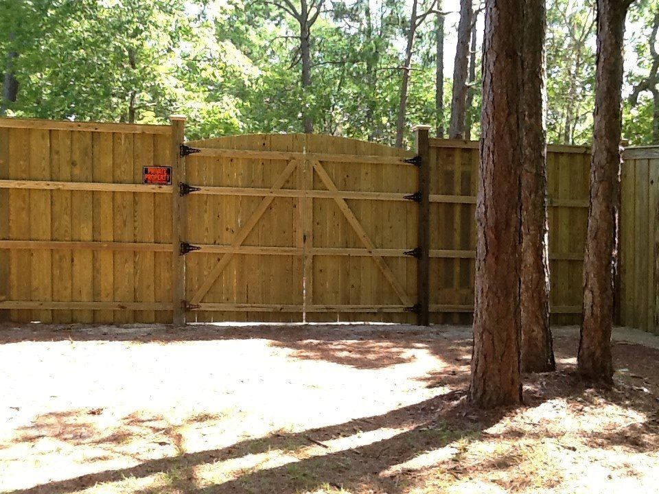 A wooden fence with a gate in the middle of a forest
