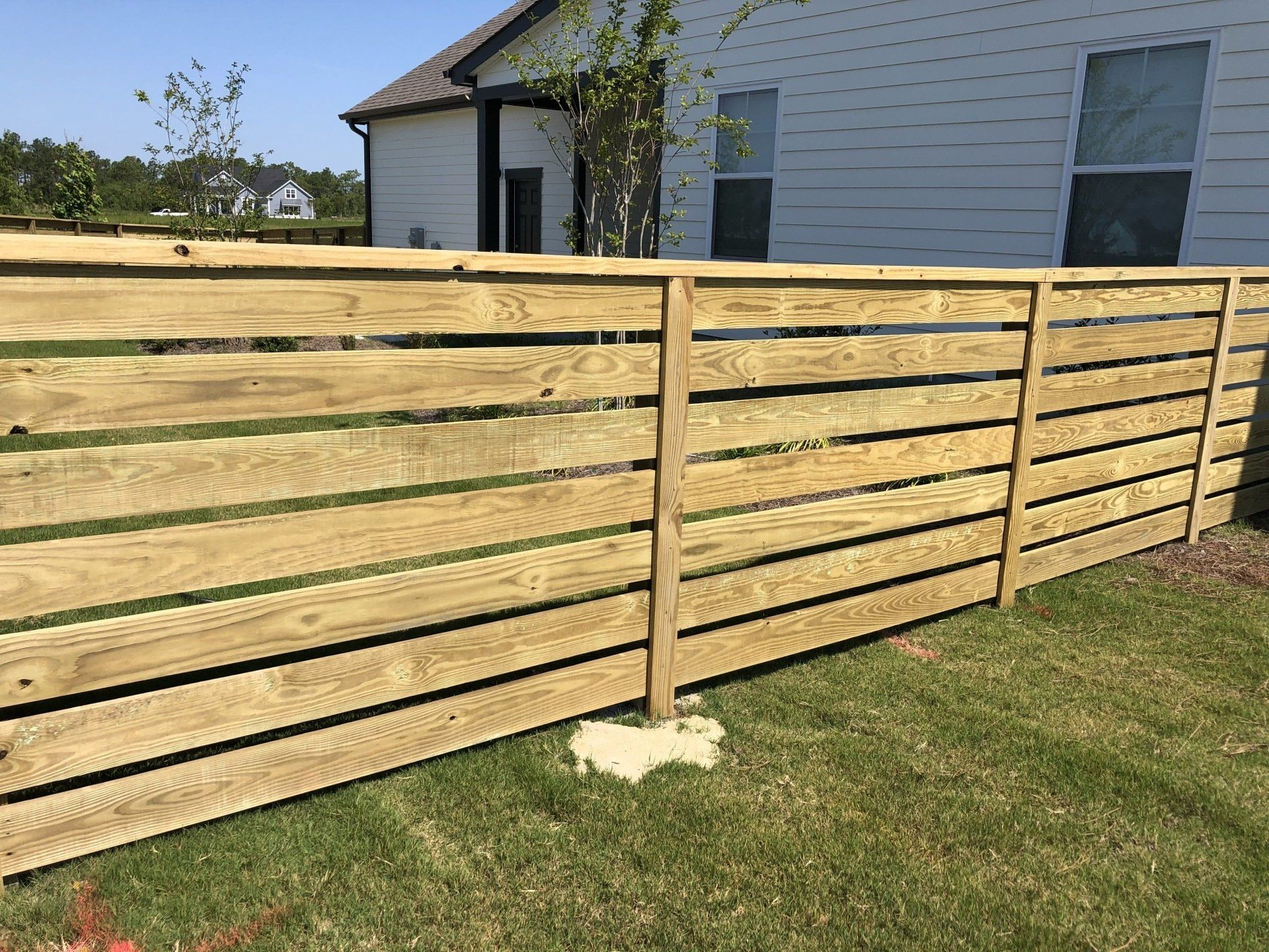 A wooden fence is sitting in the grass in front of a house.