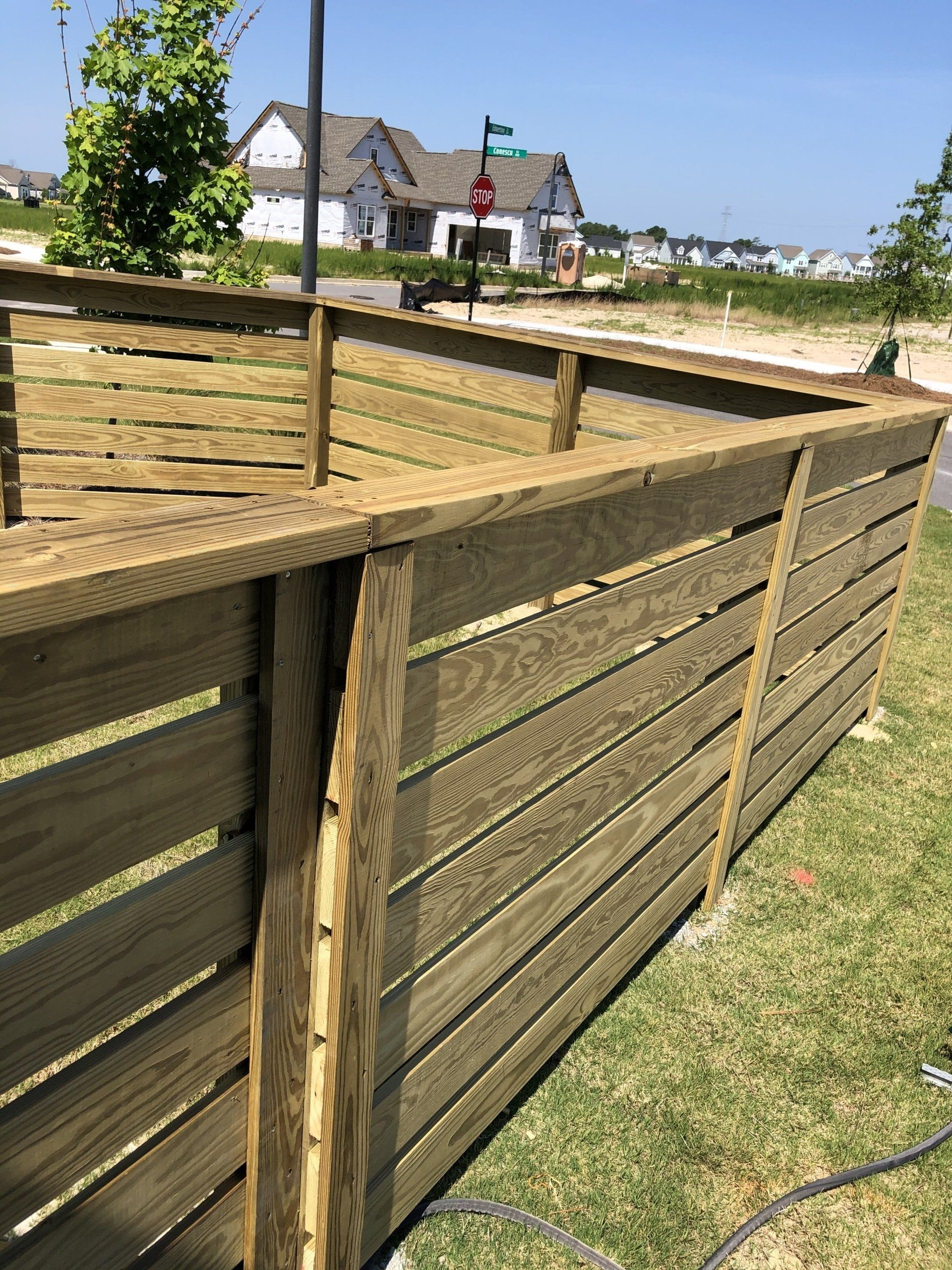 A wooden fence is sitting in the grass in front of a house.