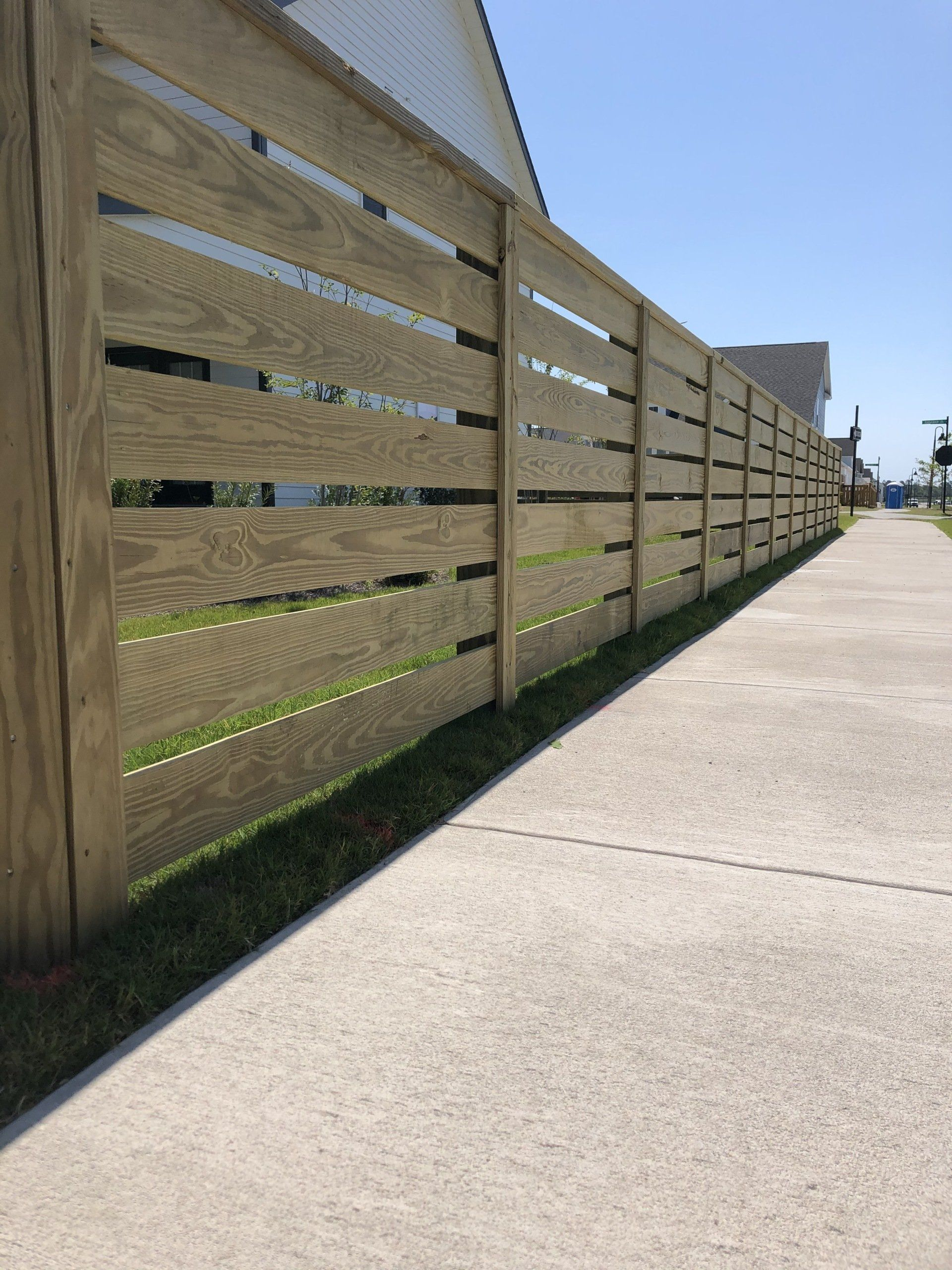 A wooden fence along a sidewalk next to a house.