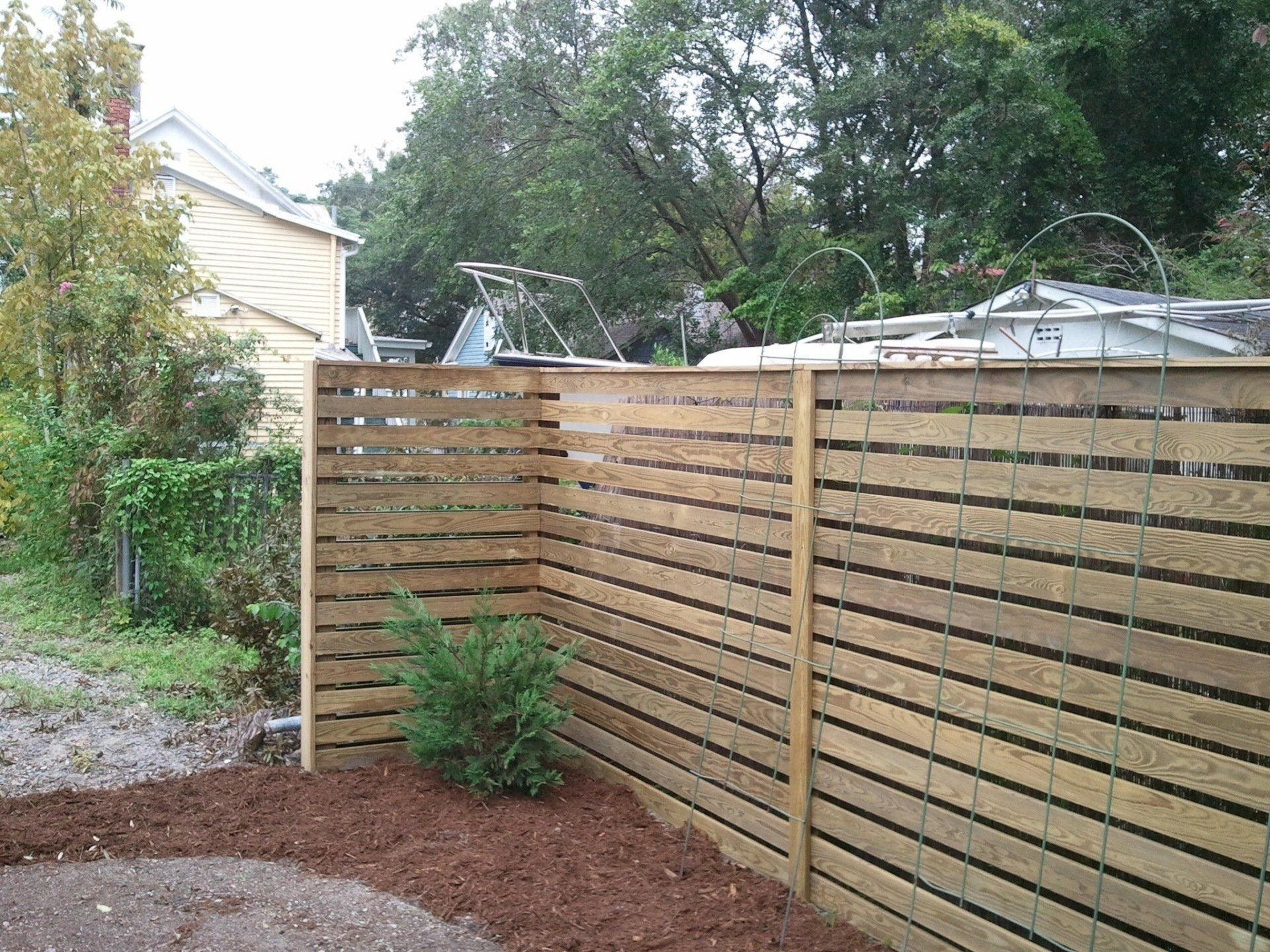 A wooden fence in a backyard with trees in the background