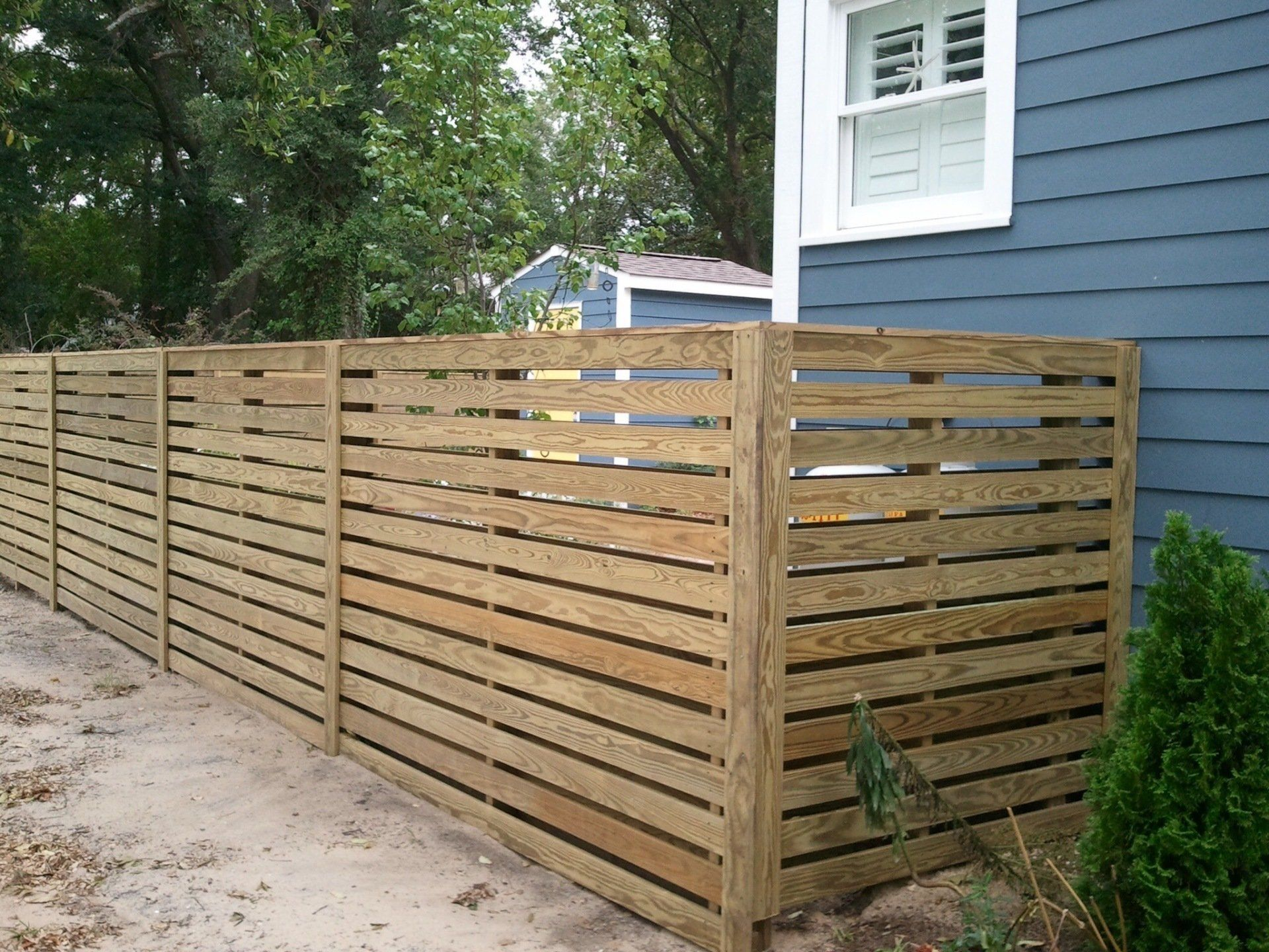 A blue house with a wooden fence in front of it