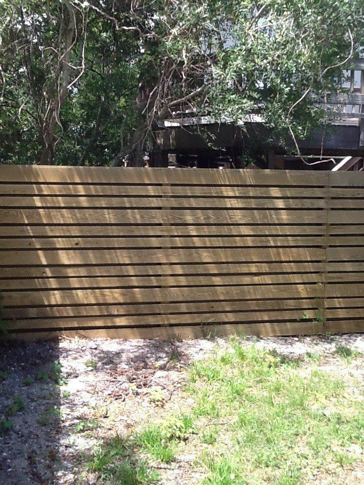 A wooden fence is surrounded by grass and trees in a backyard.
