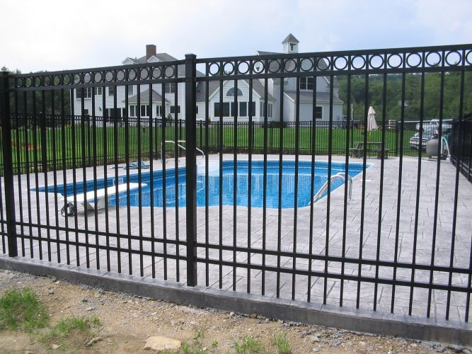 A black metal fence surrounds a swimming pool