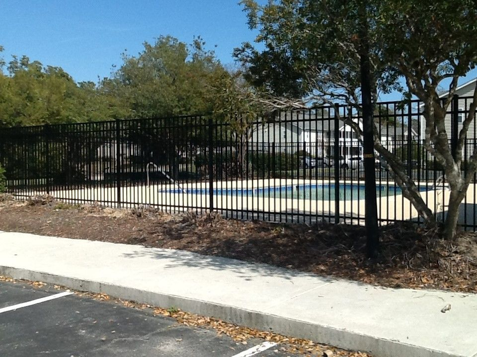 A black metal fence surrounds a swimming pool